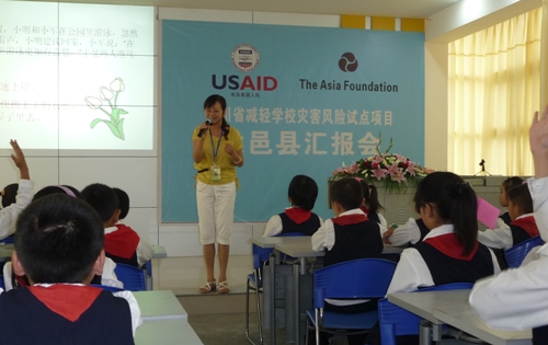 Teacher with students A teacher in China teaches her students about disaster risk reduction